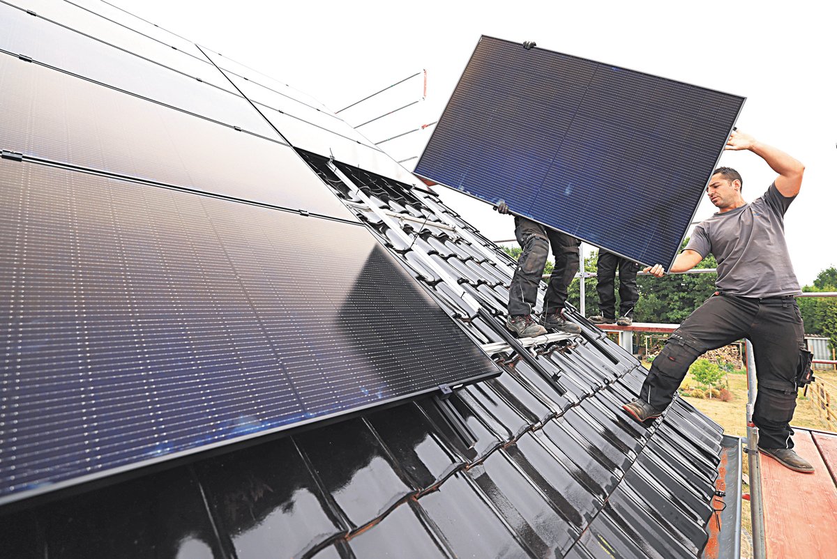 Северный Рейн-Вестфалия, Неттерсхайм. Рабочие устанавливают солнечные панели на крыше жилого дома. Фото: Oliver Berg / picture alliance / Getty Images