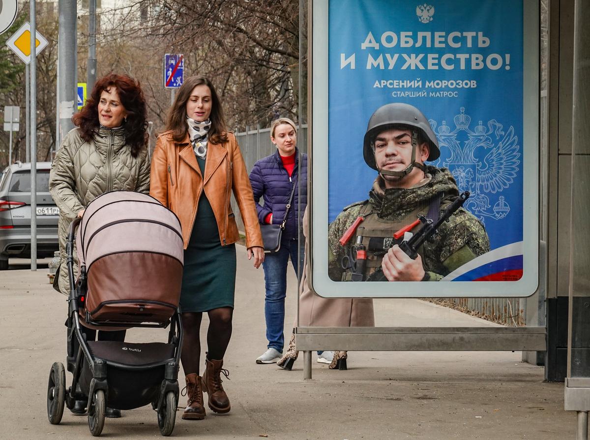 Women in Moscow walk past a poster promoting enlistment in the Russian military, 8 April 2024. Photo: EPA-EFE / YURI KOCHETKOV