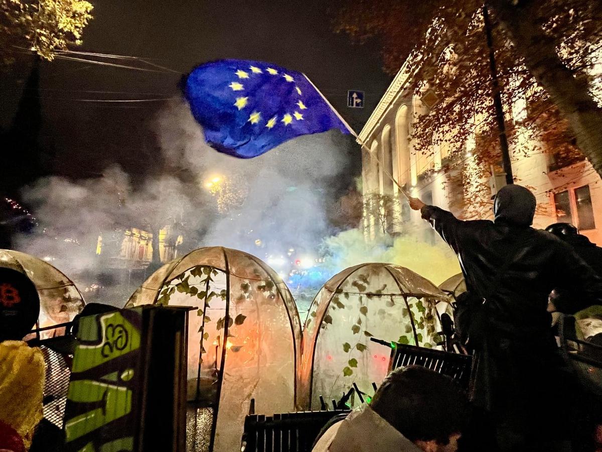 A protester waves a EU flag from behind the barricade in Tbilisi on 30 November. Photo: Nicholas Pearce for Novaya Gazeta Europe