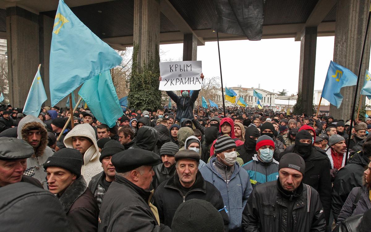 Крымскотатарские активисты держат крымскотатарские флаги и транспарант с надписью «Крым = Украина!» во время акции протеста у здания парламента в Симферополе, 26 февраля 2014 г. Фото: EPA/ARTUR SHVARTS