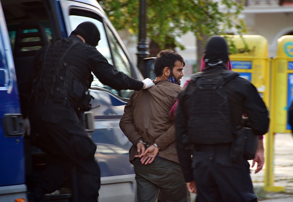 Сотрудники спецназа греческой полиции ведут 27-летнего мужчину из Таджикистана, которому предъявлены обвинения в принадлежности к ИГИЛ, Нафплион, Пелопоннес, Греция, 5 ноября 2020 года. Фото: Evangelos Bougiotis/EPA-EFE