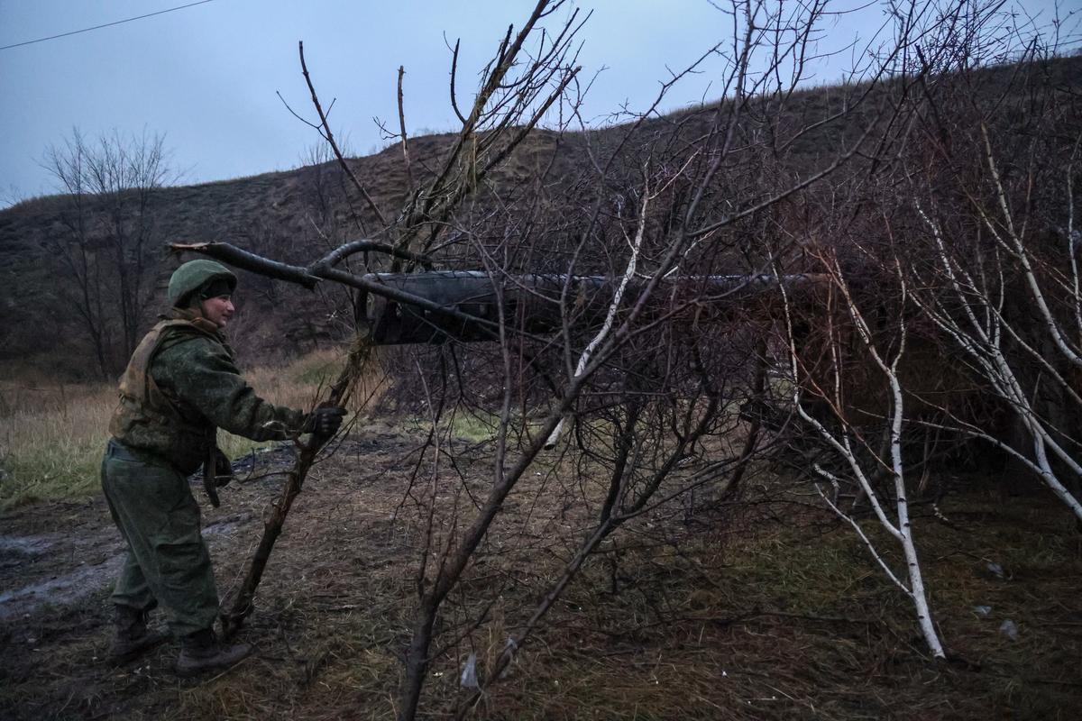 Боец самопровозглашенной ДНР подкладывает ветки деревьев над 152-мм полевой пушкой 2А36 «Гиацинт-Б» на позиции недалеко от Авдеевки, Донецкая область, восточная Украина, 22 ноября 2022 года. Фото: Алессандро Гуэрра / EPA-EFE