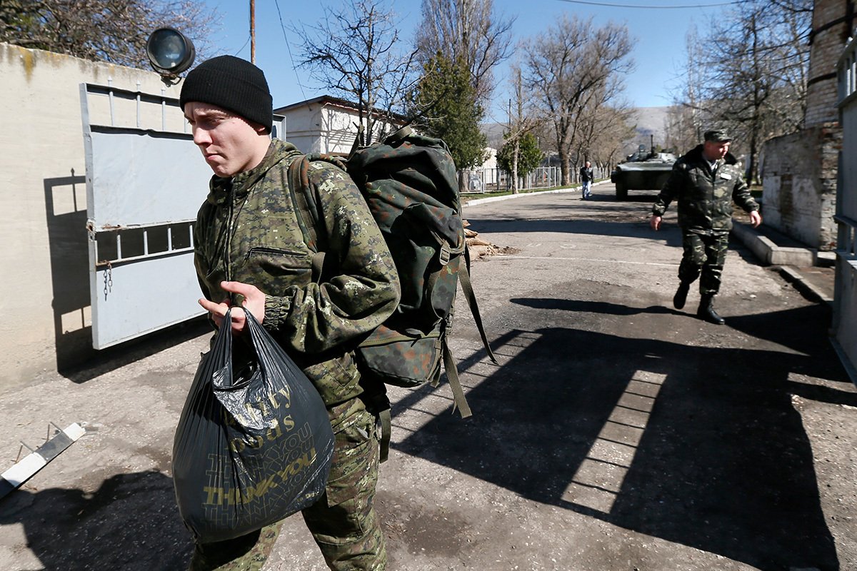 Украинский военнослужащий покидает территорию воинской части, захваченной российскими солдатами в селе Перевальное под Симферополем, Украина, 21 марта 2014 года. Фото: Юрий Кочетков / EPA