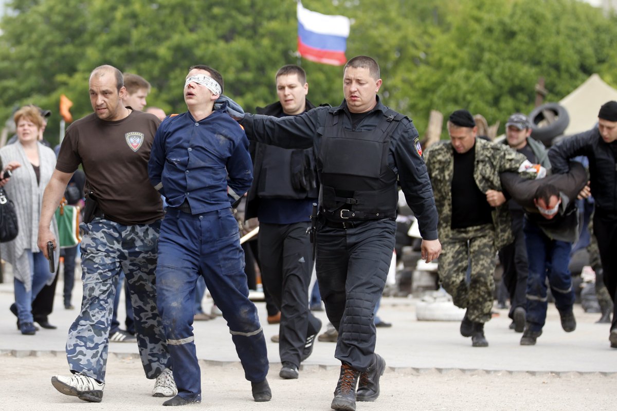 Пророссийские сторонники ведут неизвестного мужчину перед захваченным зданием областной администрации в Донецке, 5 мая 2014 года. Фото: Максим Шипенков / EPA