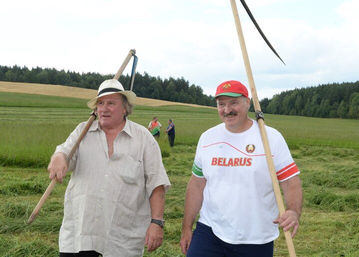 French actor Gérard Depardieu and Alexander Lukashenko carry scythes as they walk through the grounds of the official presidential residence outside Minsk, 22 July 2015. Photo: EPA / ANDREI STASEVICH