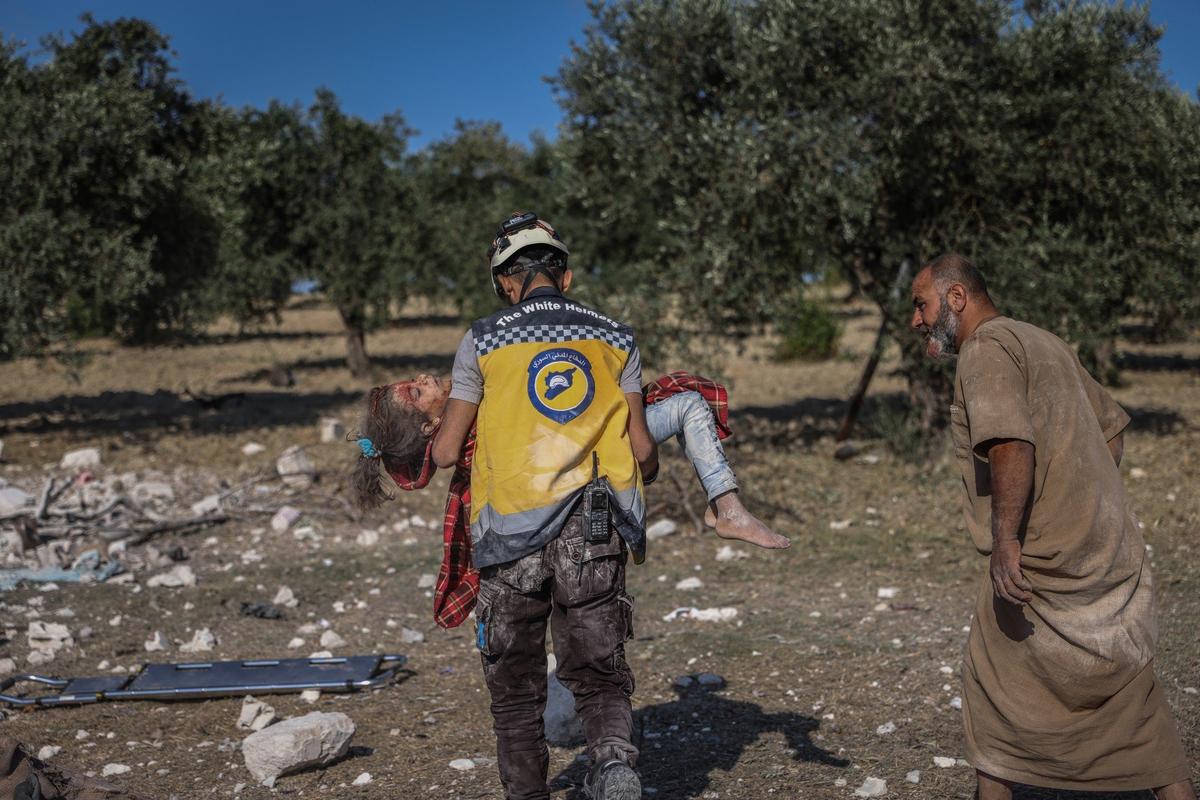 A member of the White Helmets carries the body of a girl who was killed as a result of a Russian air strike targeted a house in the town of Al-Jadida in Idlib. Photo by Anas Alkharboutli / picture alliance / Getty Images