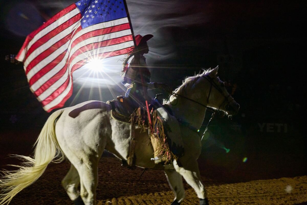 Девушка-ковбой проносит флаг США по арене в Форт-Уэрте под национальный гимн США. Фотограф: Gabriela Hasbun для Bloomberg Pursuits