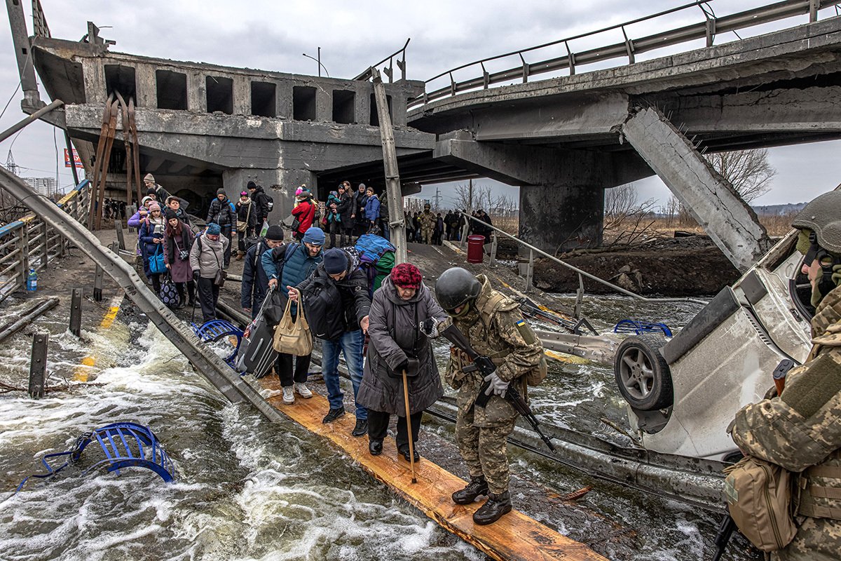 Towns in the Kyiv region, among them Bucha and Irpin, were heavily hit as Russian troops advanced on Kyiv, then still hoping to take it in three days. Photo: Refugees flee the town of Irpin over a collapsed bridge in March 2022. Photo: EPA-EFE/ROMAN PILIPEY