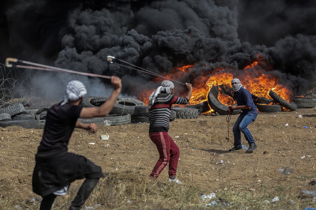 Палестинские протестующие бросают камни во время столкновений после протестов у границы с Израилем, в восточной части города Газа, 27 апреля 2018 года. Фото: Mohammed Saber / EPA-EFE