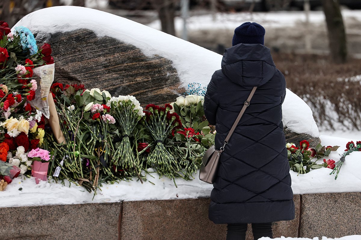 Женщина кладет цветы у памятника политзаключенным на Лубянской площади в Москве, 17 февраля 2024 года. Фото: Сергей Ильницкий / EPA-EFE