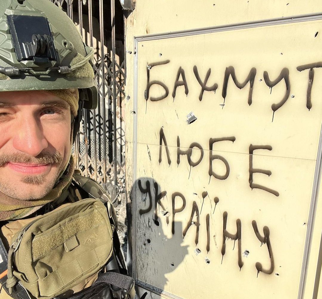 Verzilov stands next to graffiti that reads ”Bakhmut loves Ukraine” in the city of Bakhmut, eastern Ukraine, in January. Photo: Instagram