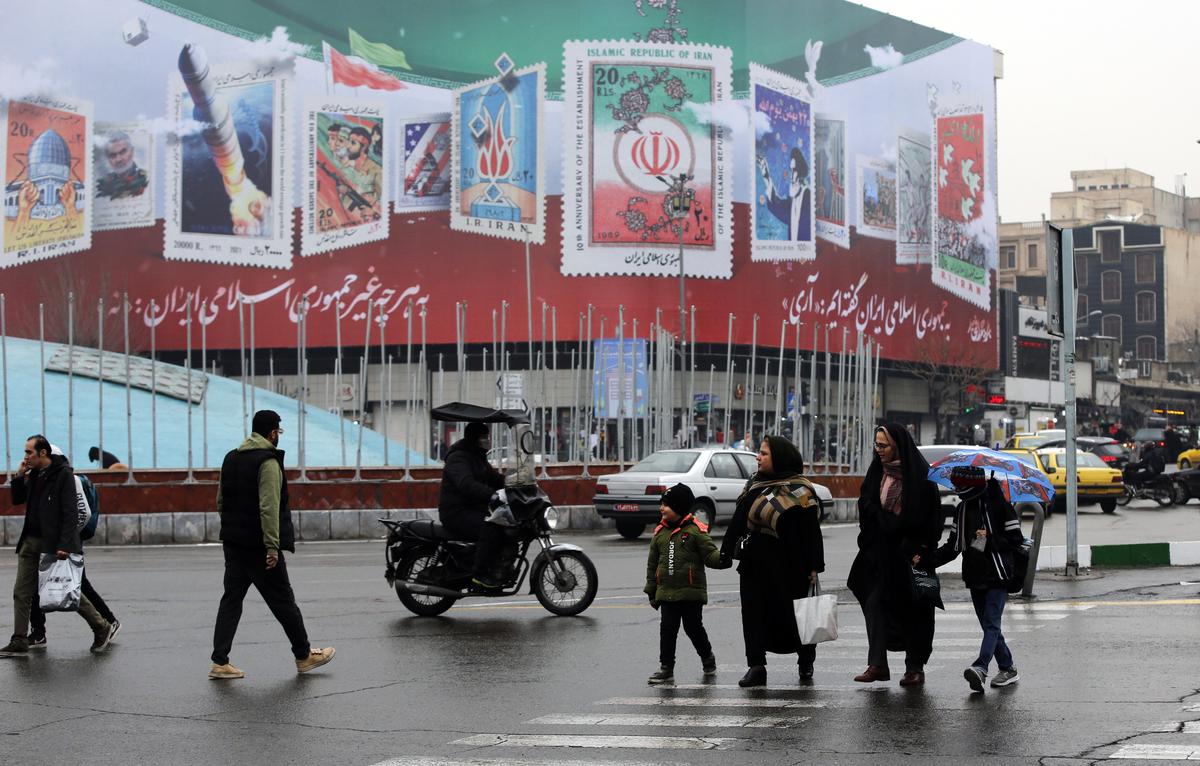 Иранцы проходят мимо рекламного щита с надписью: «Нет ничему, кроме Иранской Исламской Республики» и «Мы сказали «да» Иранской Исламской Республике» на площади Энгелаб (Революции) в центре Тегерана, Иран, 15 февраля 2023 года. Фото: EPA-EFE/ABEDIN TAHERKENAREH