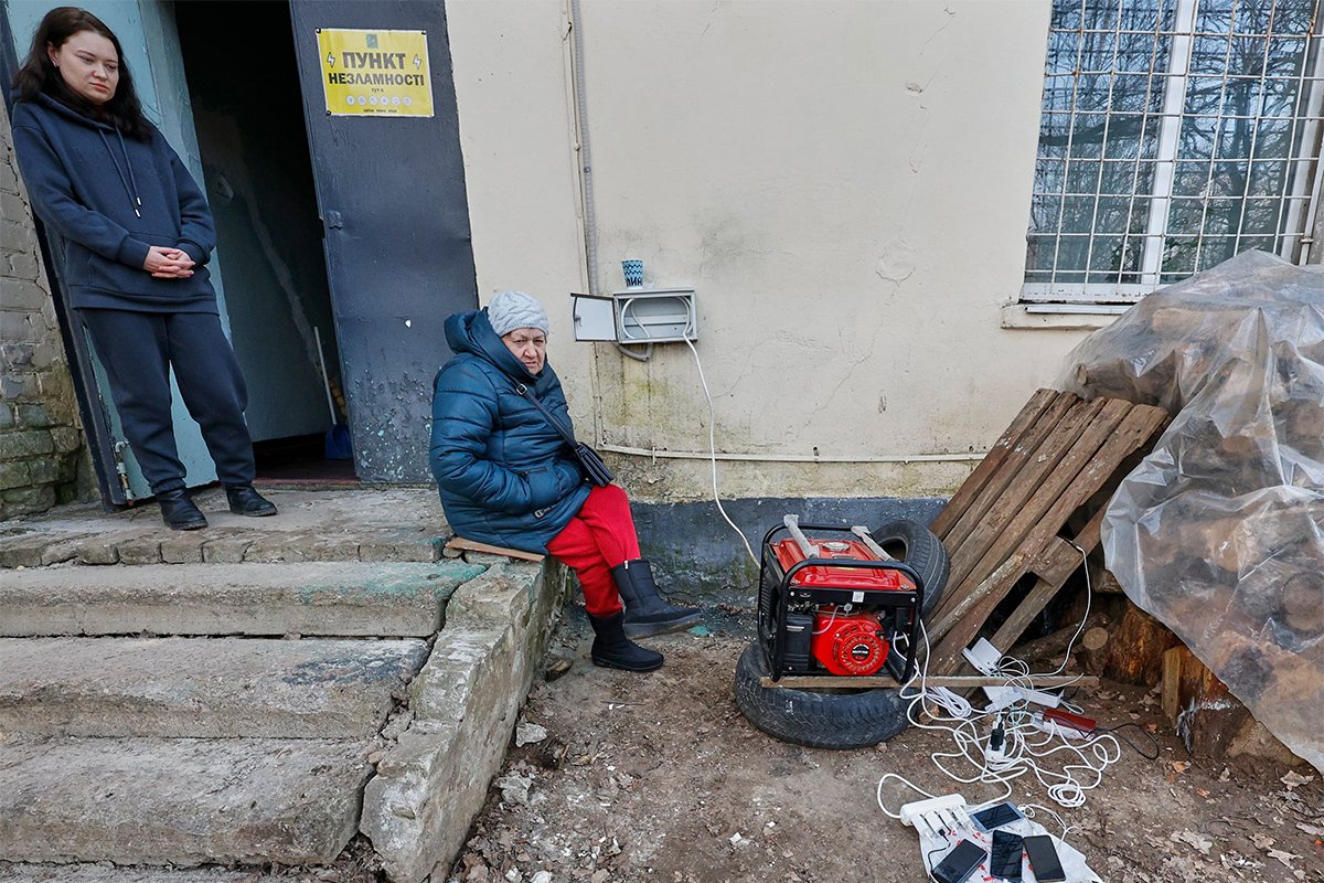 Люди собираются чтобы зарядить свои мобильные телефоны от генератора в одном из «Пунктов несокрушимости» после ракетного удара по высоковольтным линиям в Харькове, Украина, 22 марта 2024 года. Фото: Сергей Козлов / EPA-EFE