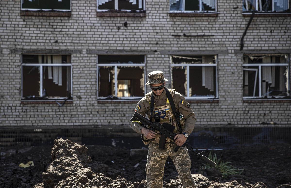 Украинский военный возле разрушенного здания школы в Харькове. Фото: Metin Aktas / Anadolu Agency / Getty Images