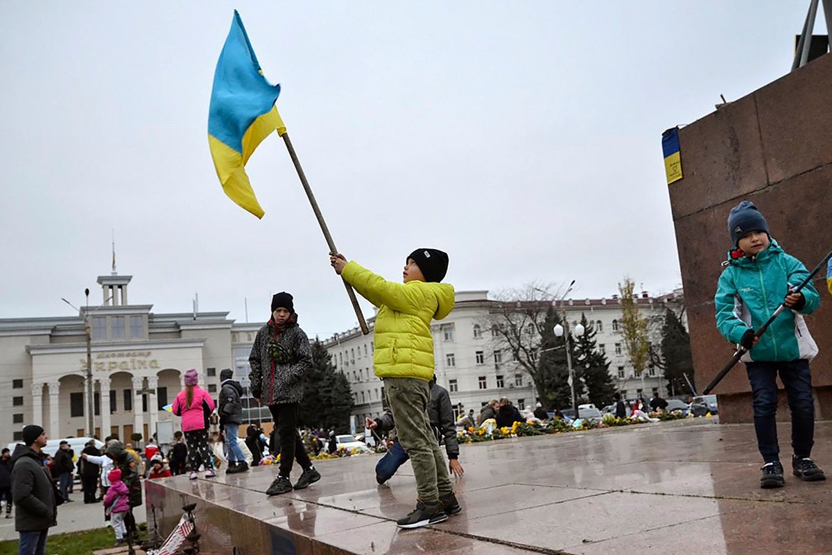 Fëmijët valëvisin flamujt ukrainas në sheshin kryesor të Khersonit pas çlirimit të qytetit nga ushtria ukrainase, Ukrainë, 13 nëntor 2022. Foto: Ivan Antipenko / EPA-EFE (redaktuar)