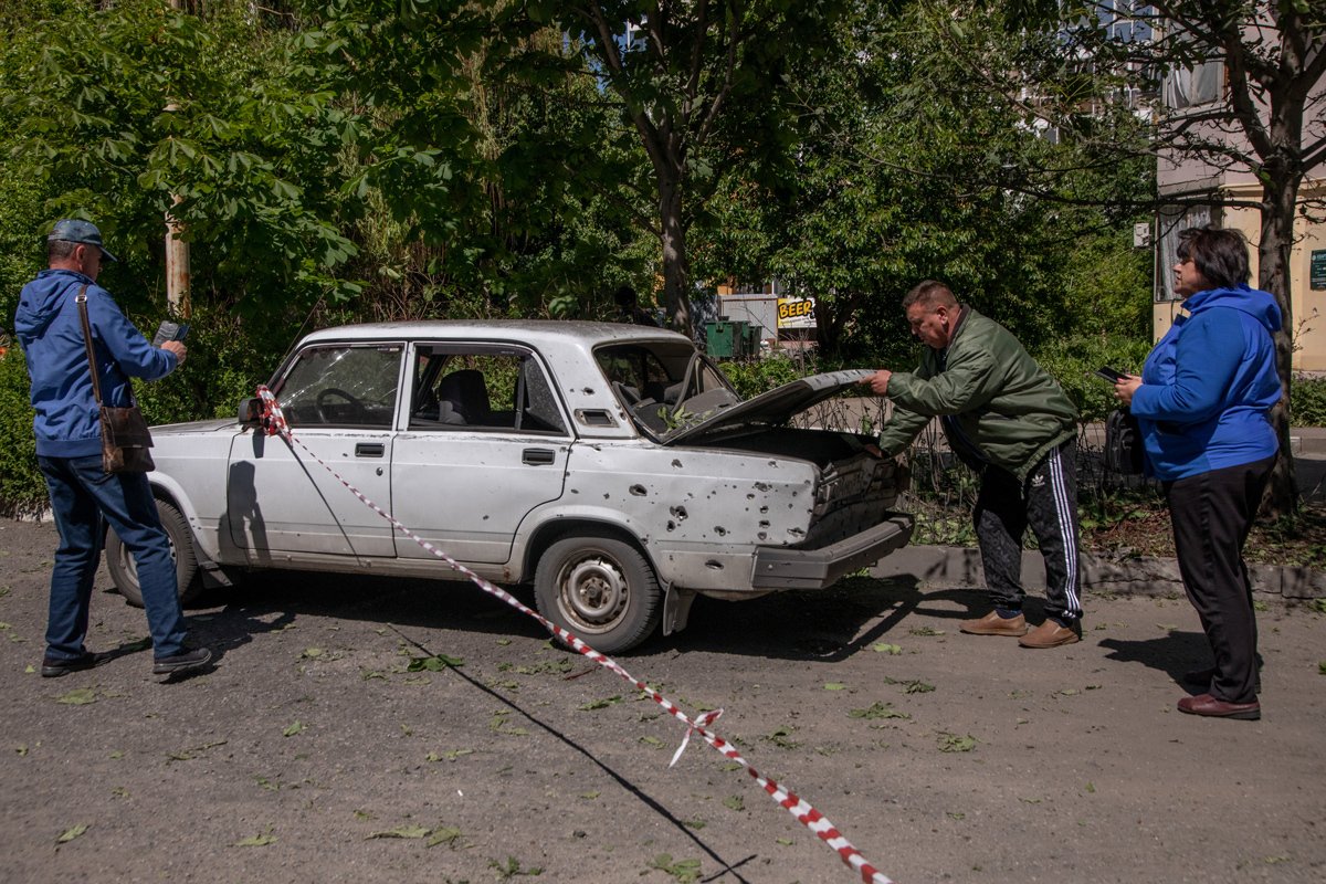 Местные жители осматривают поврежденную после очередного обстрела машину, 9 мая 2024 года. Фото: Александр Каратаев / «Новая газета Европа»