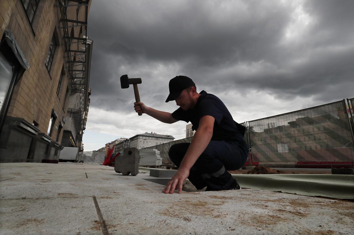 A migrant worker lays paving stones on Moscow’s Tverskaya Yamskaya Street, 19 July 2017. Photo: EPA / YURI KOCHETKOV