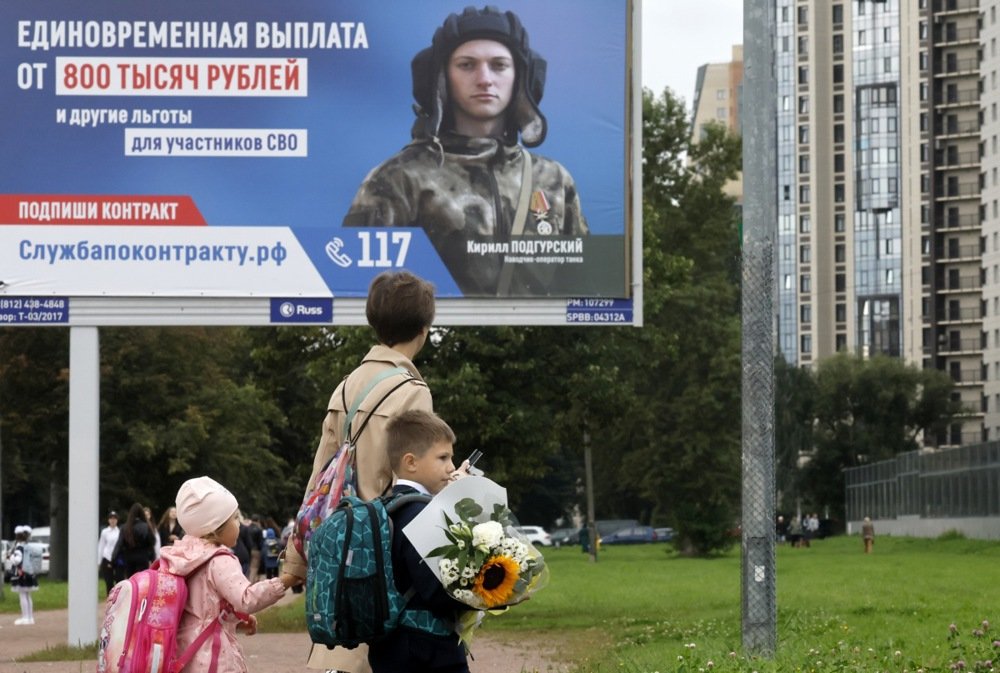 Russian schoolchildren walk past a poster showing a military conscription ad in Moscow. Photo: EPA-EFE/ANATOLY MALTSEV