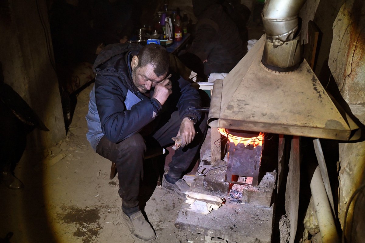 Мужчина разогревает самодельную печь в подвале дома в Левобережном районе Мариуполя, Украина, 13 апреля 2022 года. Фото: Анатолий Жданов / Коммерсантъ / Sipa USA / Vida Press