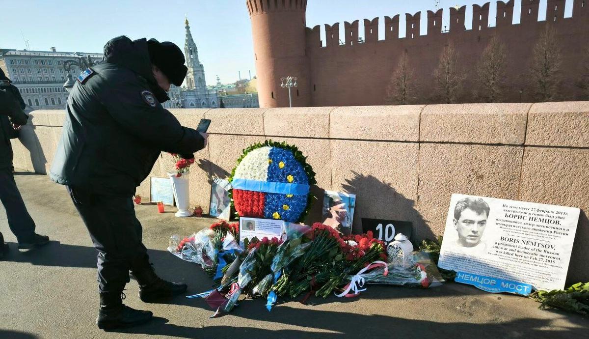 A police officer takes a picture of the Nemtsov Bridge memorial on Thursday morning. Photo: SOTAvision