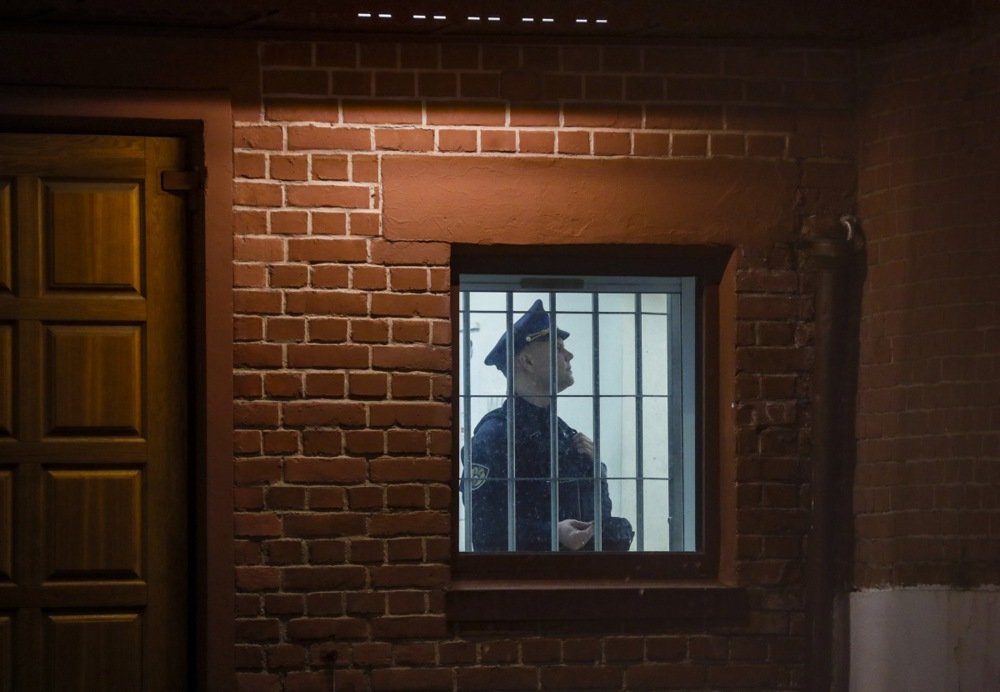 A police officer is visible through the bars on a police station window in Moscow, 12 January. Photo: EPA-EFE/YURI KOCHETKOV