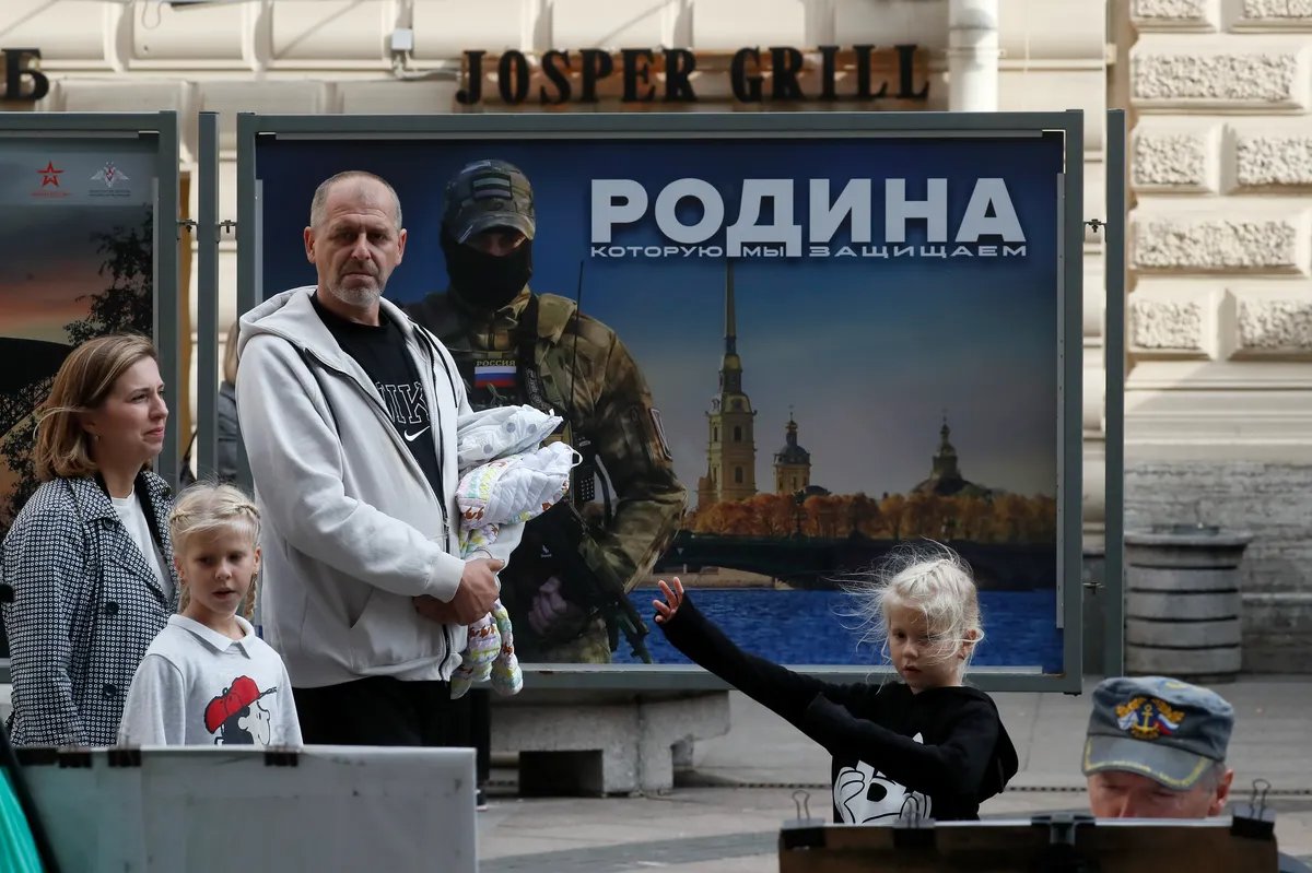 Люди проходят мимо рекламного щита, на котором изображен российский военнослужащий с надписью «Родина, которую мы защищаем» на уличной выставке военных фотографий в Санкт-Петербурге, Россия, 24 сентября 2023 года. Фото: Анатолий Мальцев / EPA-EFE