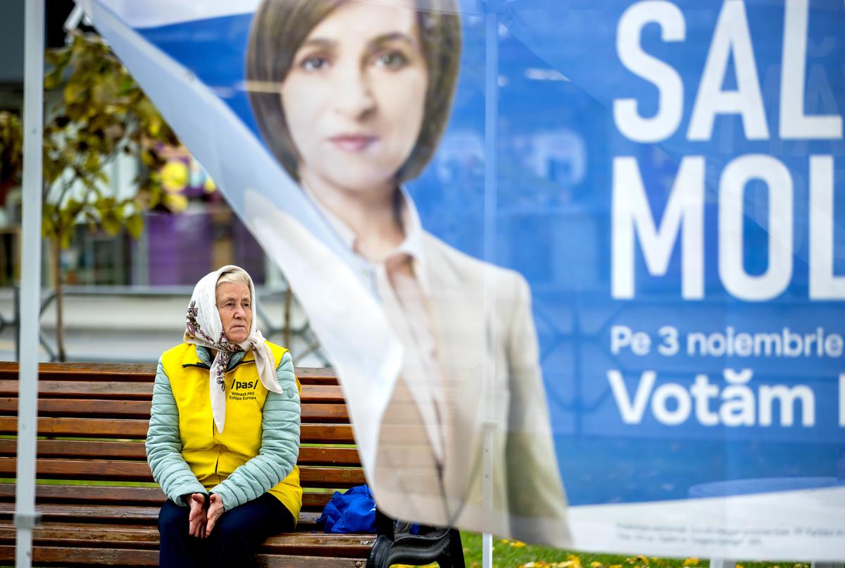 An elderly woman sits on a bench in front of an awning urging people to vote for incumbent pro-European Maia Sandu in Chisinau, Moldova, 31 October 2024. Photo: EPA-EFE / DUMITRU DORU