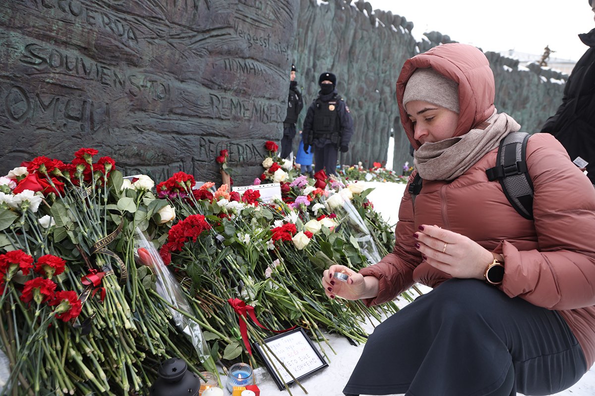 Женщина ставит свечу в память об Алексее Навальном у монумента «Стена скорби» в Москве, 17 февраля 2024 года. Фото: Contributor / Getty Images