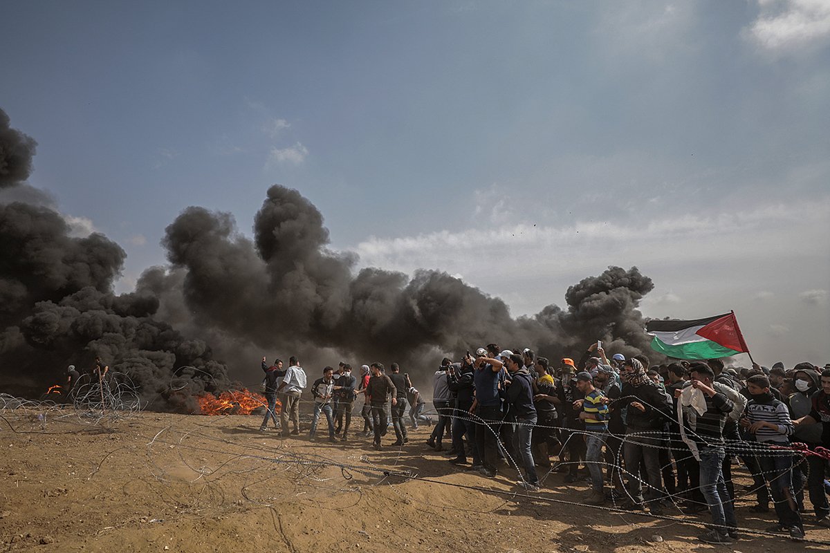 Палестинские демонстранты укрываются во время столкновений после пятничных протестов у границы с Израилем в восточной части города Газа, Сектор Газа, 27 апреля 2018 года. Фото: Mohammed Saber / EPA-EFE