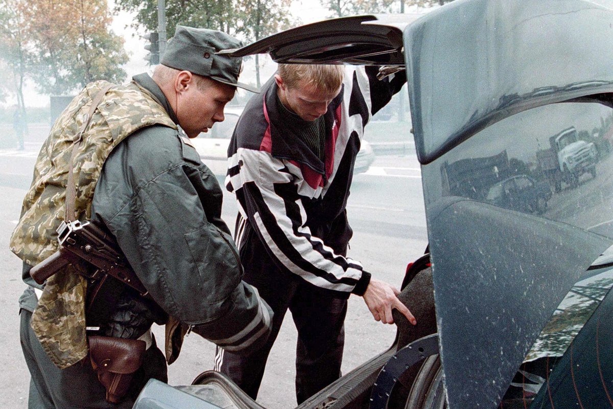 Полицейский осматривает багажник автомобиля на дороге в Санкт-Петербург, 16 сентября 1999 года. Фото: Анатолий Мальцев / EPA