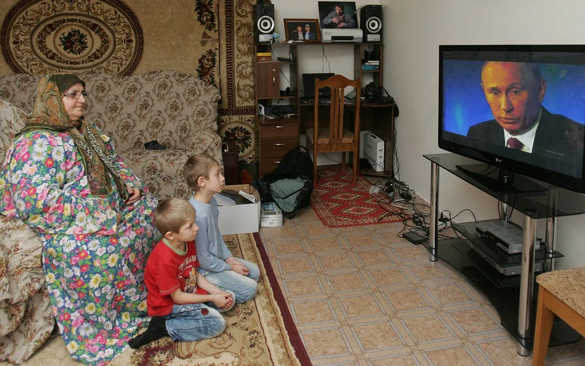 A Chechen woman and her grandchildren watch a live broadcast of a Putin press conference in the village of Alkhan-Kala, near the Chechen capital Grozny, 20 December 2012. Photo: Kazbek Vakhaev / EPA