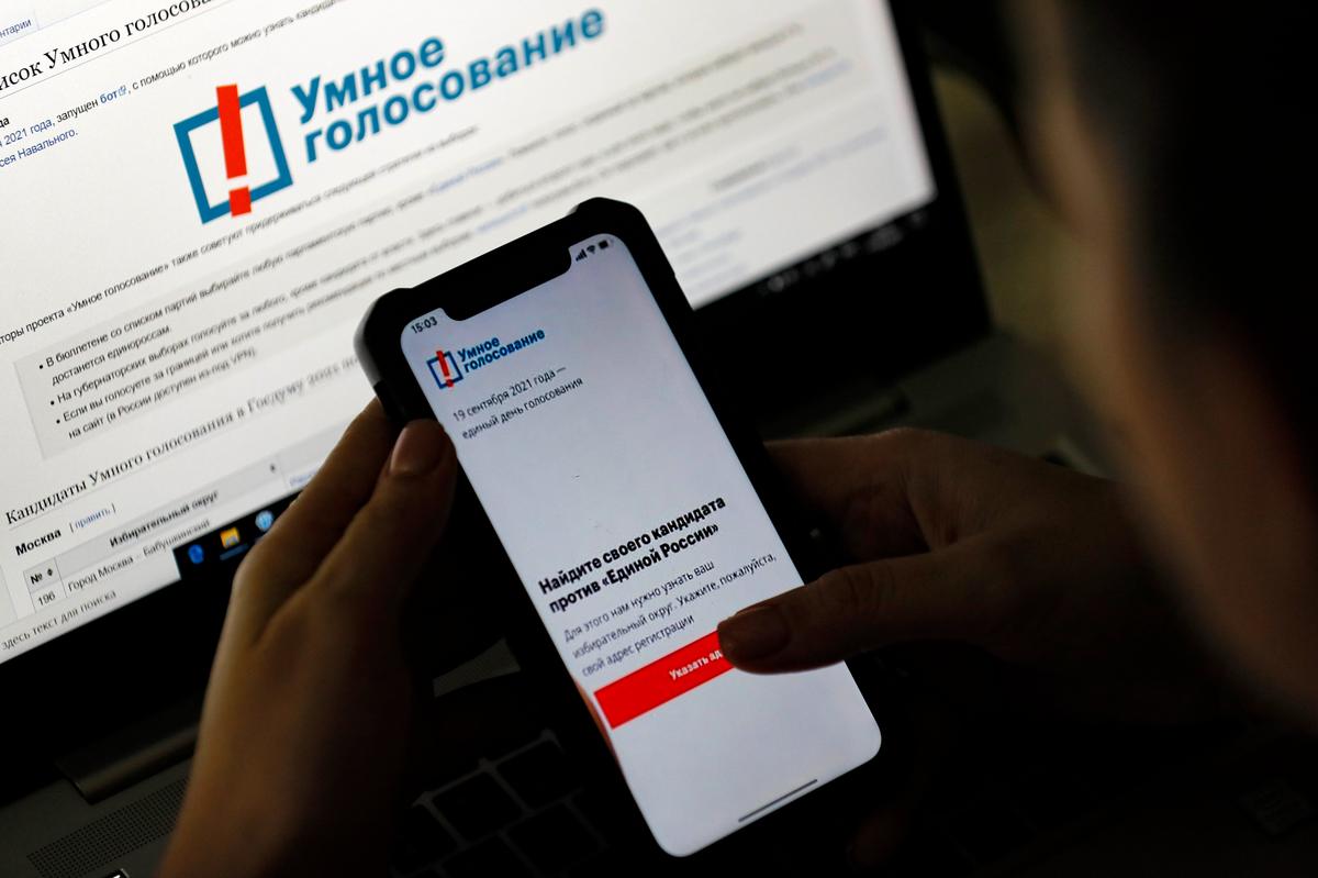 Женщина рассматривает приложение Навального «Умное голосование» на своем телефоне в Москве, 17 сентября 2021 года. Фото: Сергей Ильницкий / EPA-EFE