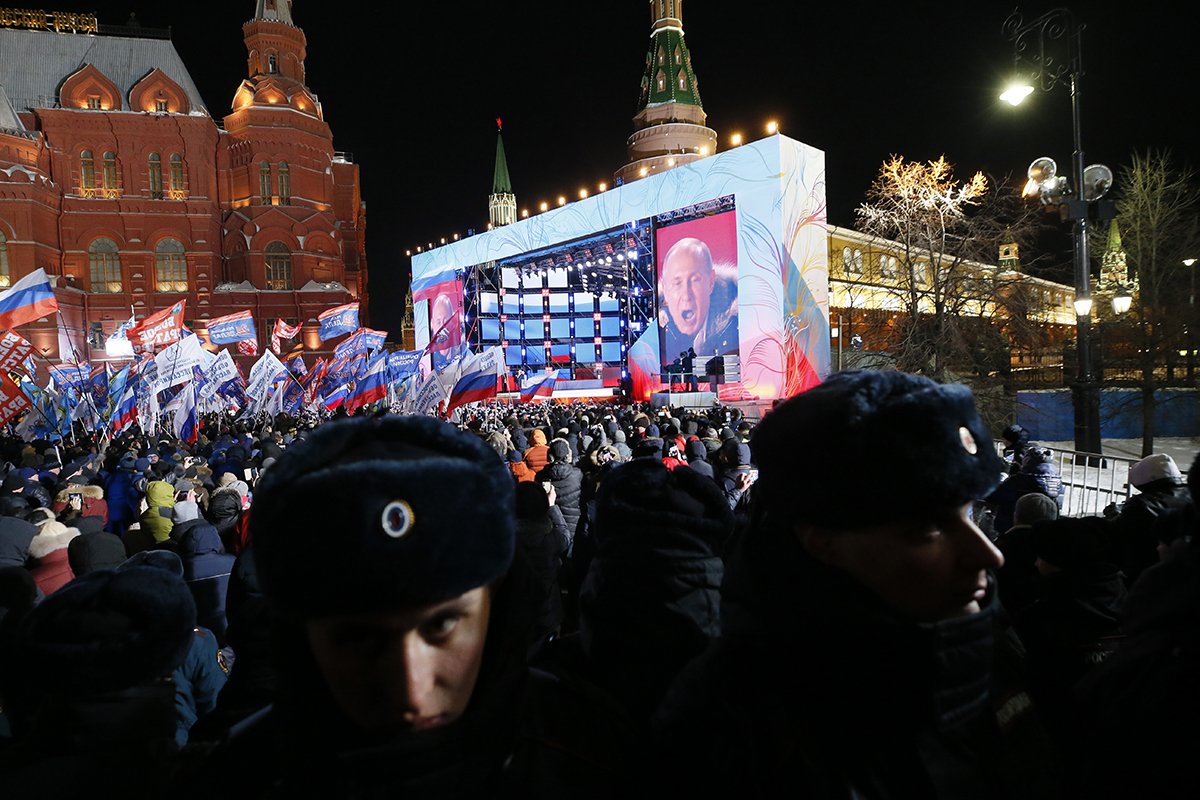 На экране Владимир Путин, кандидат в президенты, выступающий во время митинга в свою поддержку возле Кремля в Москве, Россия, 18 марта 2018 года. Фото: Максим Шипенков / EPA-EFE