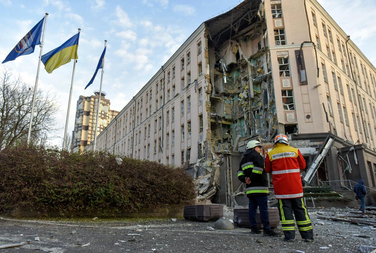 Украинские спасатели стоят перед поврежденным зданием гостиницы, пострадавшим в результате ракетного удара, в центре Киева, 31 декабря 2022 года. Фото: EPA-EFE/OLEG PETRASYUK