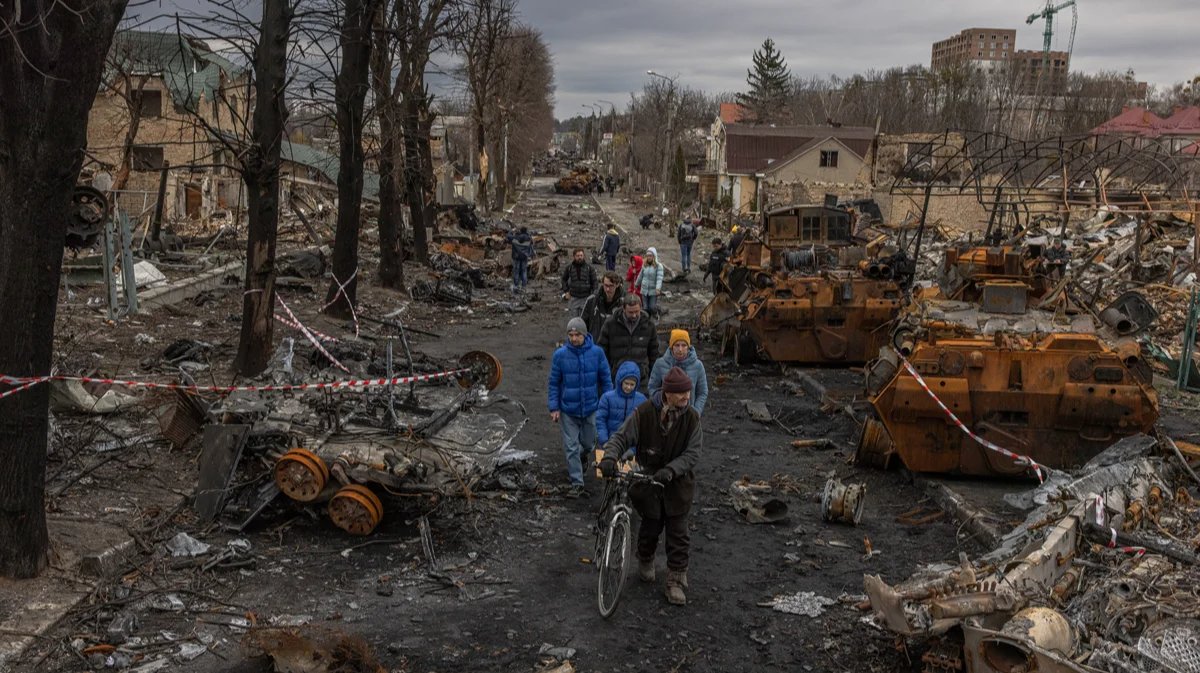 Bucha residents walk past burnt out Russian military equipment on 6 April 2022. Photo: Roman Pilipey / EPA-EFE