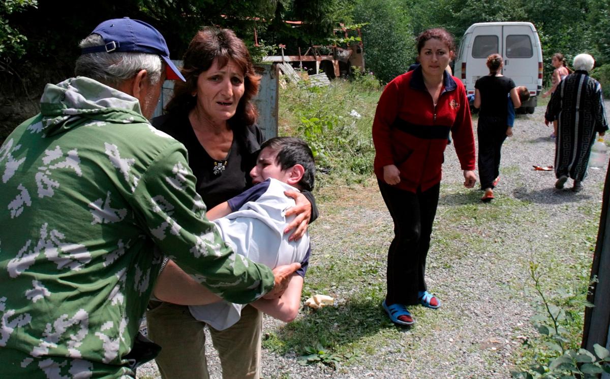 Жители Южной Осетии несут раненого ребенка в селе Джава, Грузия, 9 августа 2008 г. Фото: EPA/YURI KOCHETKOV