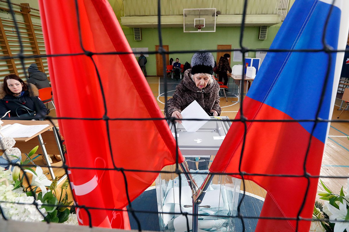 Женщина отпускает свой бюллетень в урну для голосования на выборах президента России на избирательном участке в Санкт-Петербурге, Россия, 18 марта 2018 года. Фото: Анатолий Мальцев / EPA-EFE