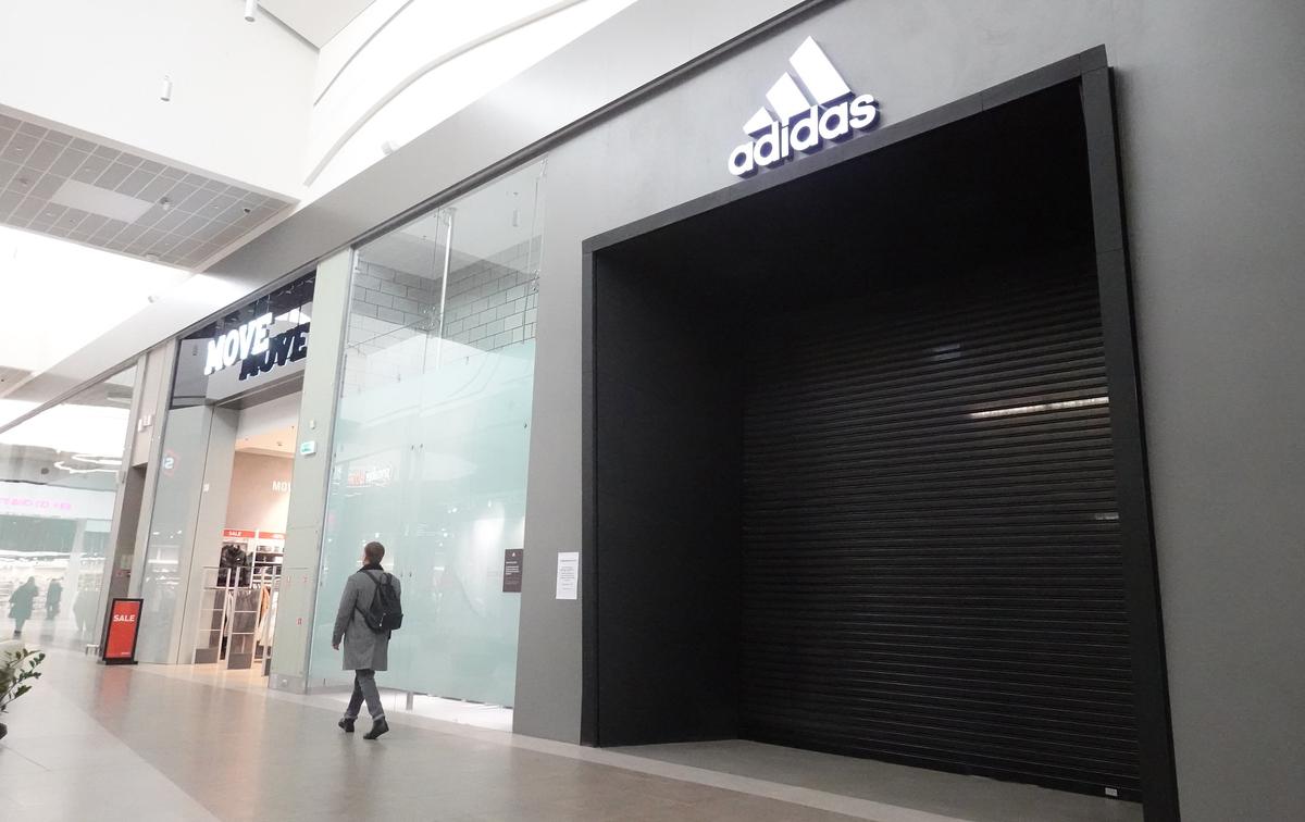 Покупатели идут перед закрытым магазином Adidas в торговом центре «Мега» в Москве. Фото: Максим Шипенков / EPA-EFE