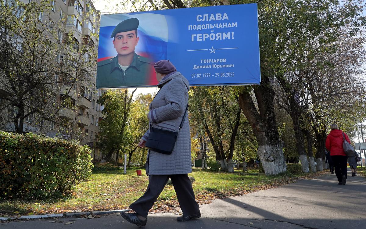 An elderly woman in the Moscow region town of Podolsk passes an awning featuring Russian soldier Daniil Goncharov, who died fighting in Ukraine, and the slogan “Glory to Podolsk’s Heroes”, 11 October 2022. Photo: EPA-EFE / MAXIM SHIPENKOV