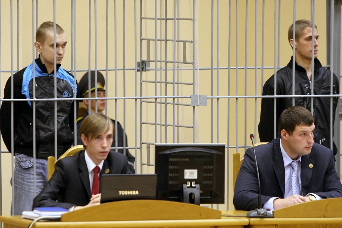 Владислав Ковалев (справа) и Дмитрий Коновалов (слева), обвиняемые в терроризме, стоят в клетке перед началом судебного заседания в Минске, 15 сентября 2011 года. Фото: Татьяна Зенькович / EPA