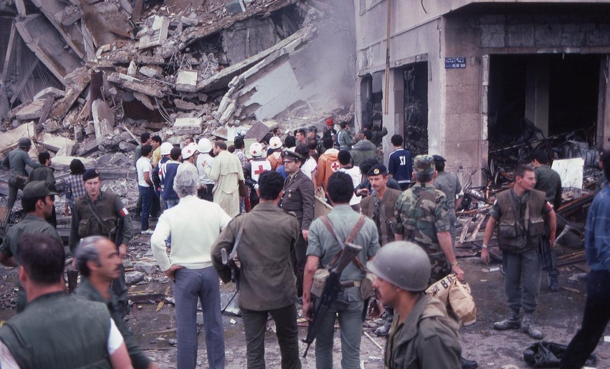 Толпа солдат и людей, оказывающих помощь, стоит на фоне разрушений, на месте взрыва смертником американского посольства, Бейрут, Ливан, 18 апреля 1983 года. Фото Peter Davis / Getty Images