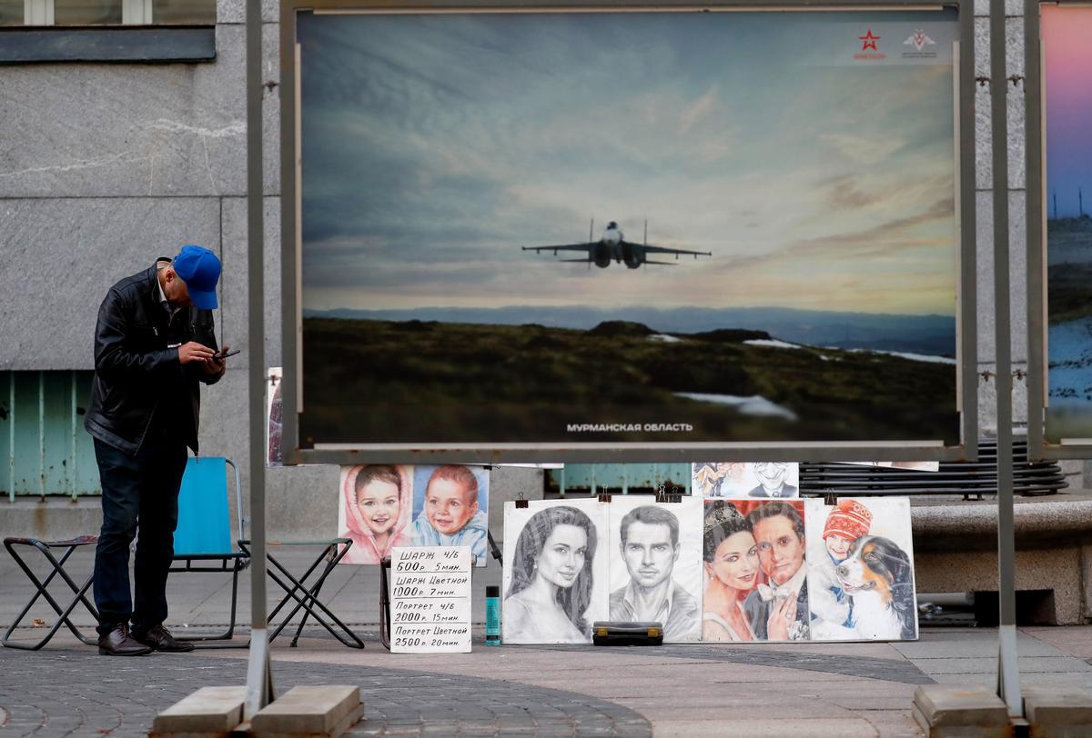 Уличный художник продает карикатуры перед уличной выставкой военных фотографий в Санкт-Петербурге, Россия, 4 сентября 2023 года. Фото: Анатолий Мальцев / EPA-EFE