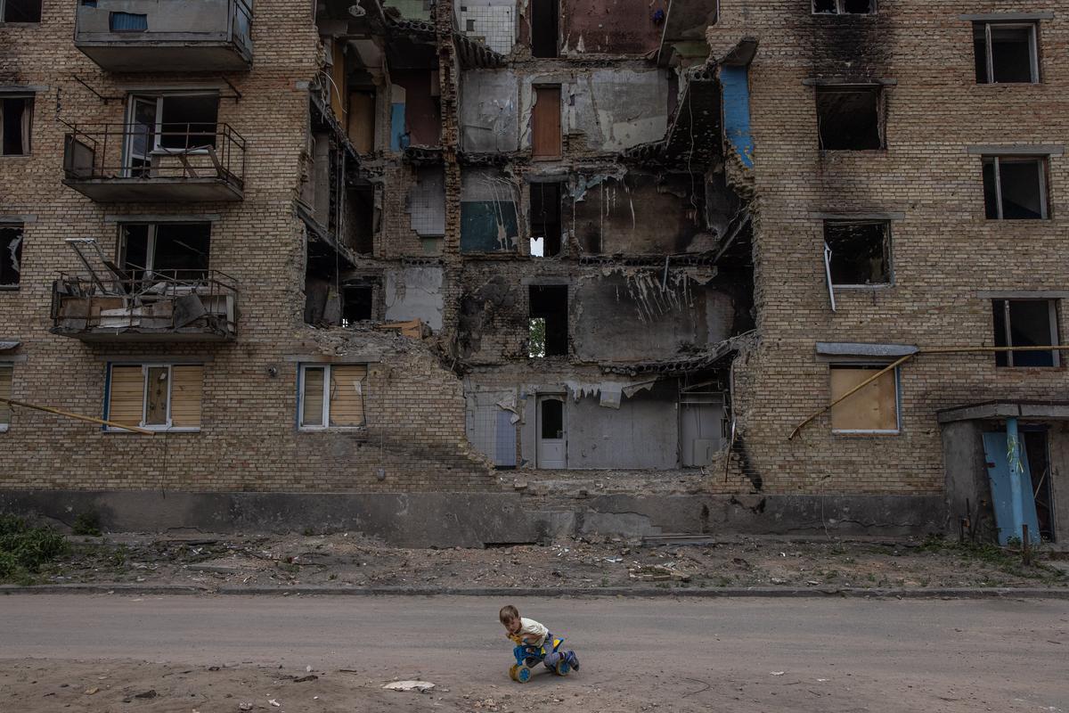 Ребенок играет перед поврежденным жилым домом в Горенке, Киевская область, июнь 2022 г. Фото: EPA-EFE/ROMAN PILIPEY