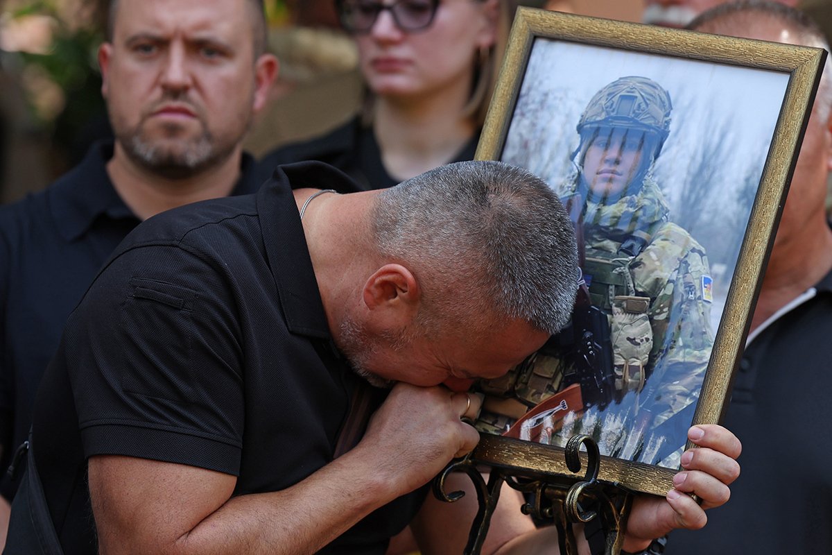 Отец украинского военнослужащего Игоря Воеводина плачет у портрета сына на похоронах в Киеве, Украина, 25 августа 2023 года. Фото: Cathal Mcnaughton / EPA-EFE