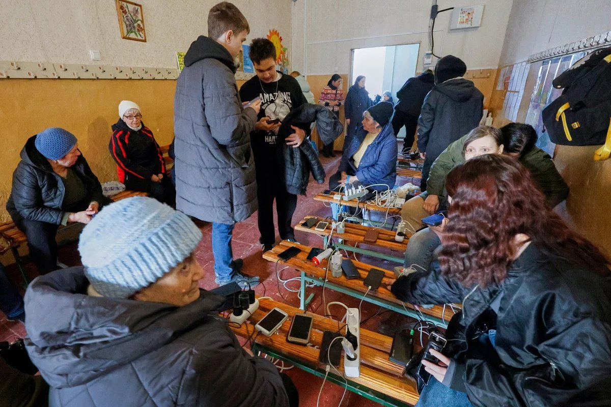 People gather to charge their phones near a generator after airstrikes on energy facilities in Kharkiv, Ukraine, 22 March 2024. Photo: Sergei Kozlov / EPA-EFE