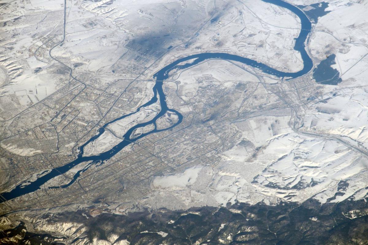 Красноярск снят с орбиты в хороший день - смога нет, юго-западный ветер. Вверху видно, кто дымит на левом берегу - черное пятно - это КрАЗ. На правом затемнения поменьше - это ТЭЦ. 
Фото: Роскосмос