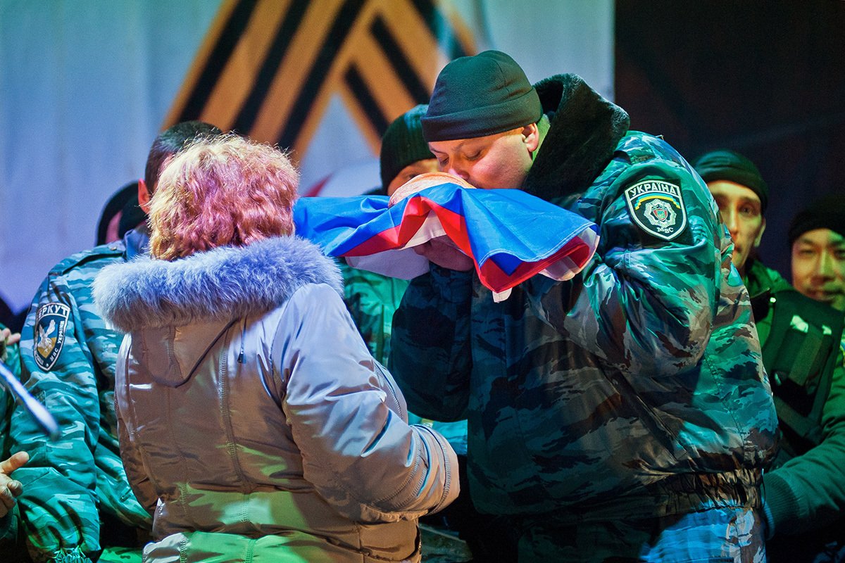 Сотрудник спецподразделения милиции «Беркут» целует российский флаг в центре Севастополя, Крым, Украина, 20 марта 2014 года. Фото: Антон Педько / EPA