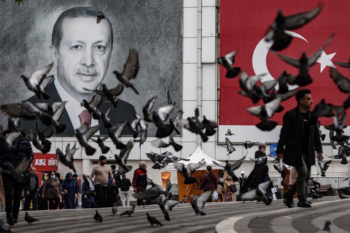 Люди проходят мимо портрета президента Турции Реджепа Тайипа Эрдогана и турецкого флага в Бурсе, Турция, 11 мая 2023 года. Фото: Erdem Sahin / EPA-EFE