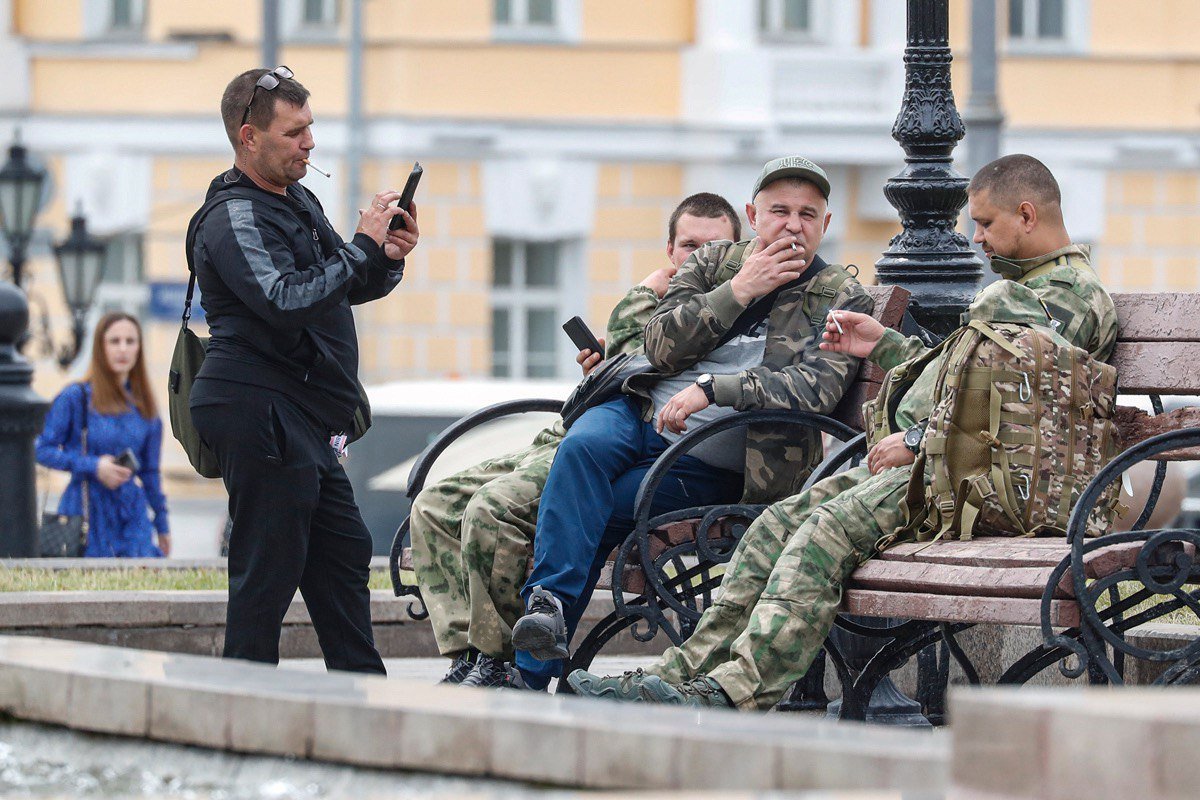 Мужчины, одетые в военную форму, отдыхают на скамейке в центре Москвы, 27 июня 2023 года. Фото: Максим Шипенков / EPA-EFE
