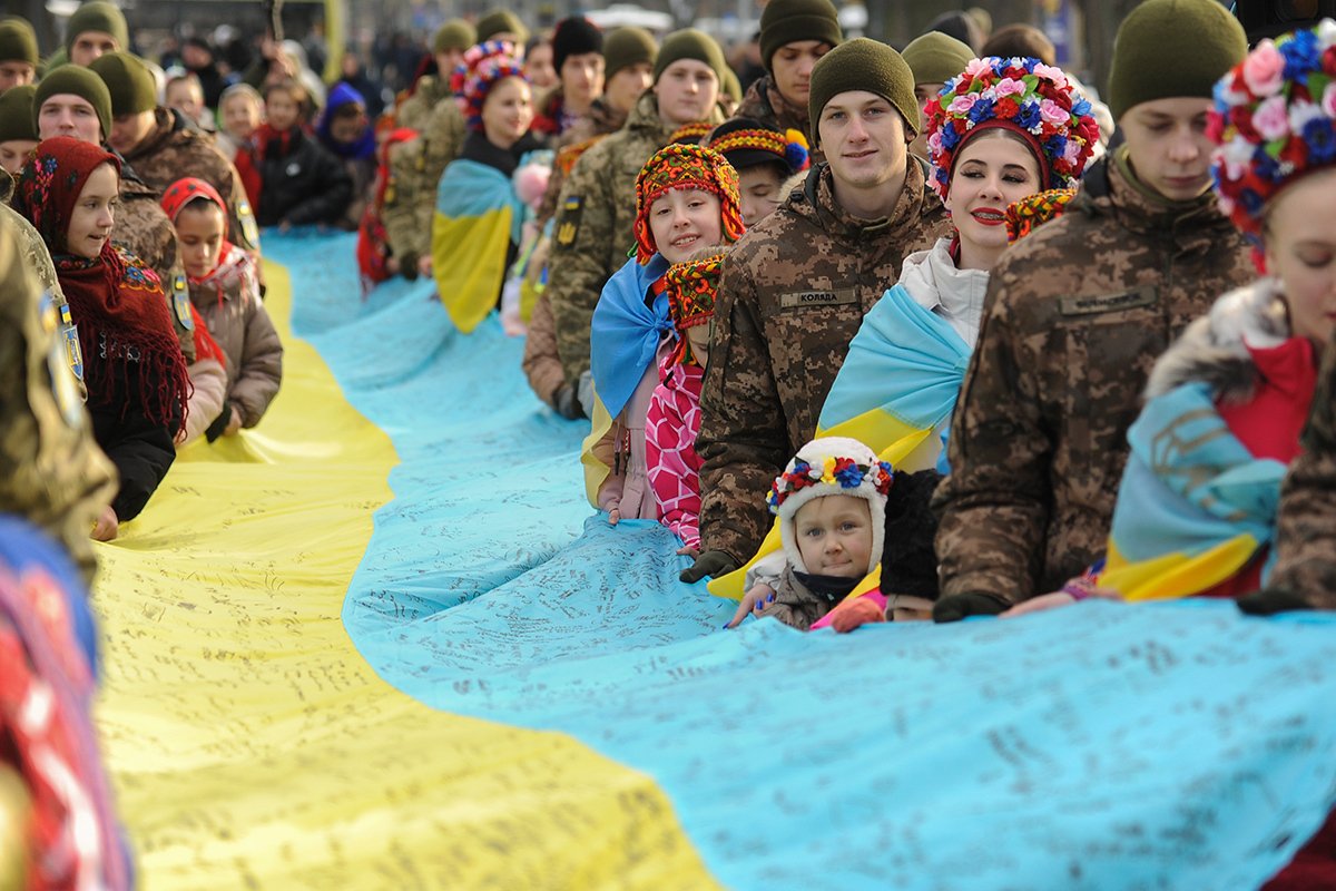 Украинцы держат 20-метровый национальный флаг, подписанный Главнокомандующим Вооруженных Сил Украины Валерием Залужным и 1447 украинскими солдатами во Львове, Украина, 21 января 2024 года. Фото: Микола Тыс / EPA-EFE